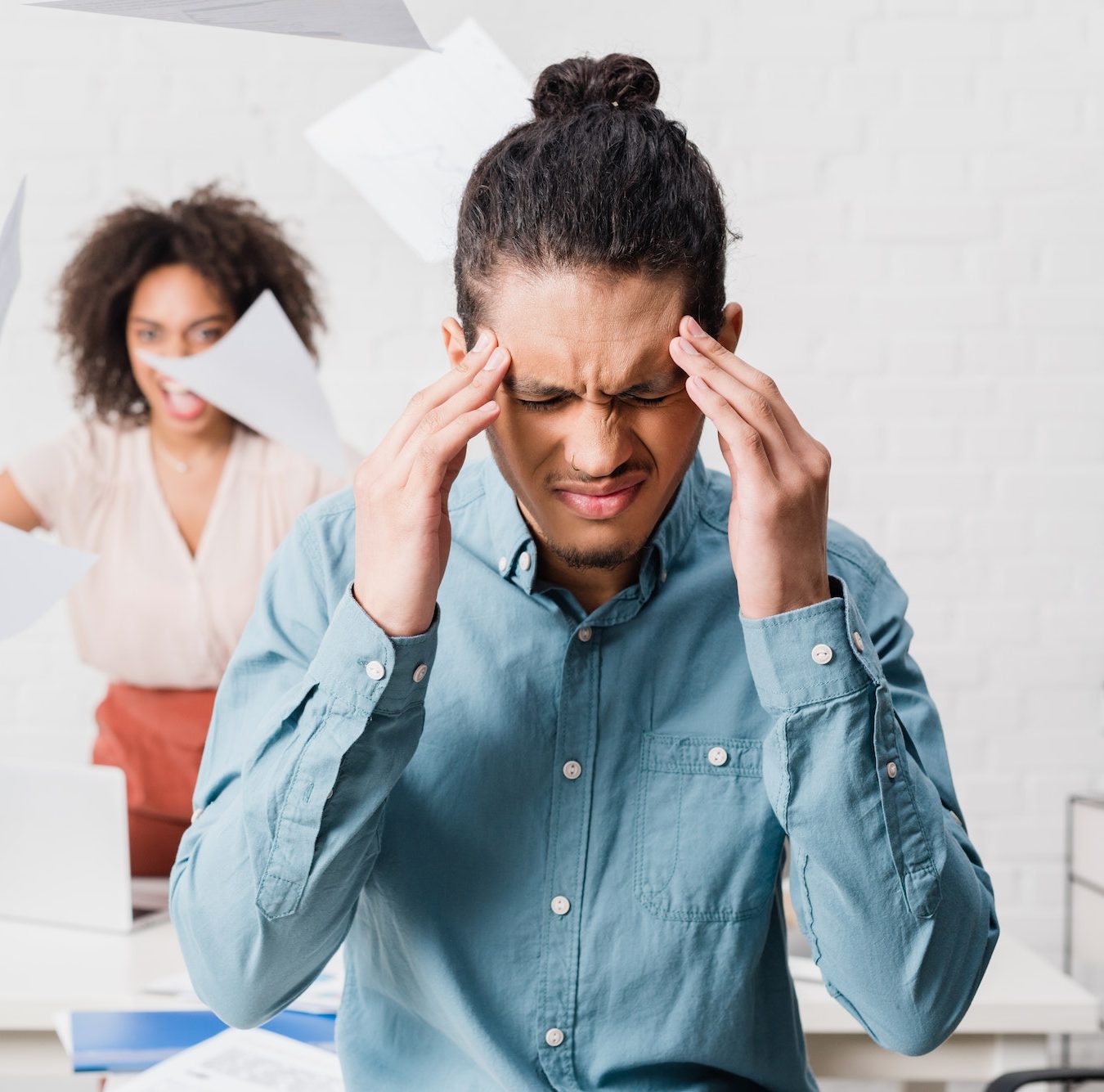 Businessman suffering from headache while his female colleague yelling in office