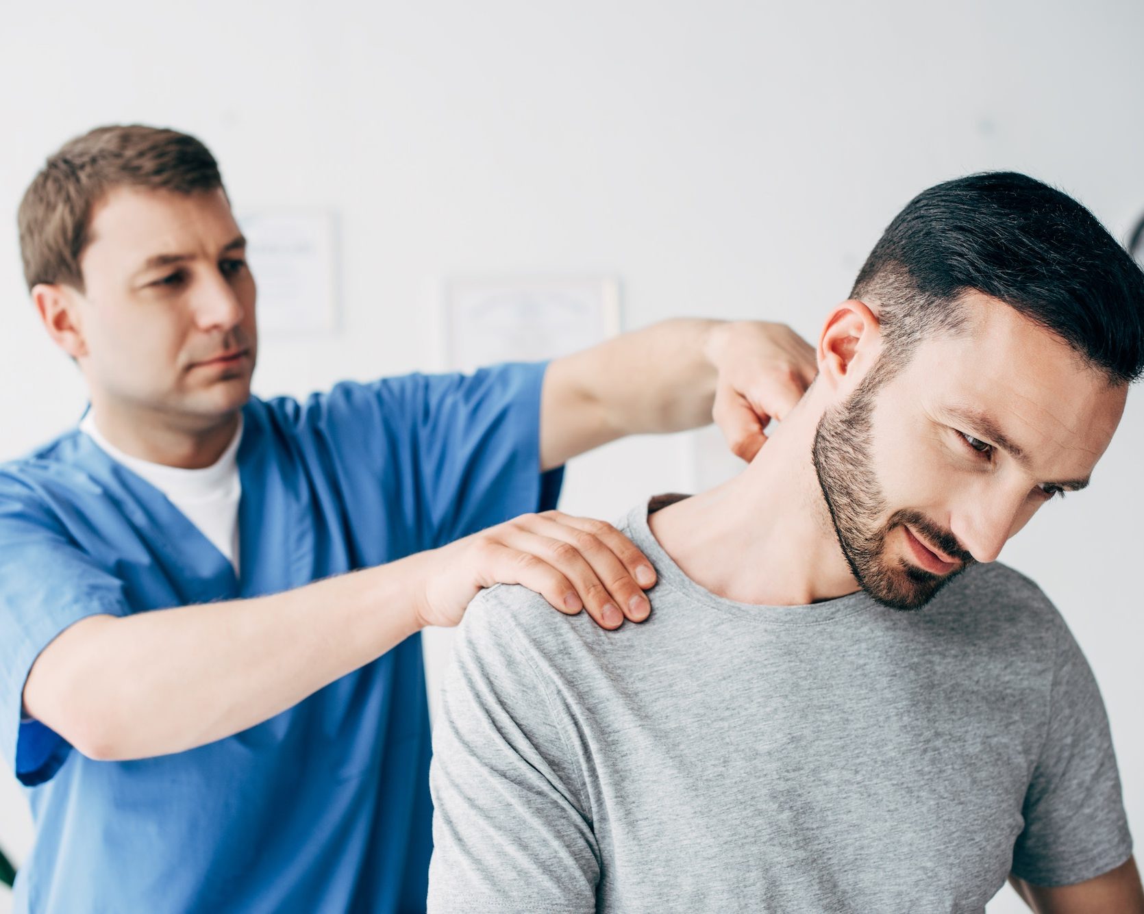 Selective focus of patient sitting on couch and doctor massaging patient neck in massage cabinet at